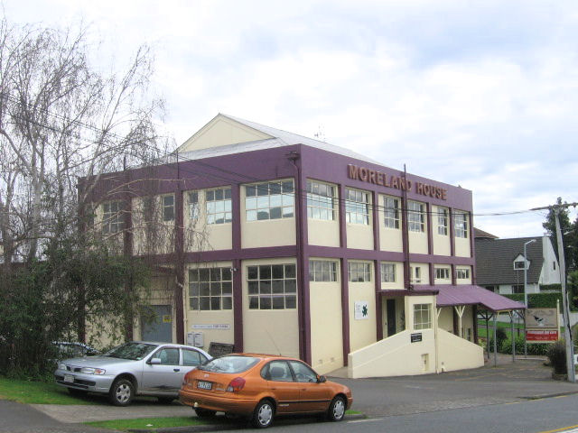 Moreland House on the corner of Eleventh Avenue and Devonport Road, Tauranga, the building painted purple with the Moreland House sign above the entrance, housing Moreland Fabrics.
