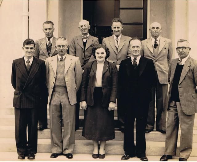 Dairy Company office and trading store staff photographed on the steps of the building on the day the new store opened. Norm Fletcher, store manager until 1969, is front row, second from left.
